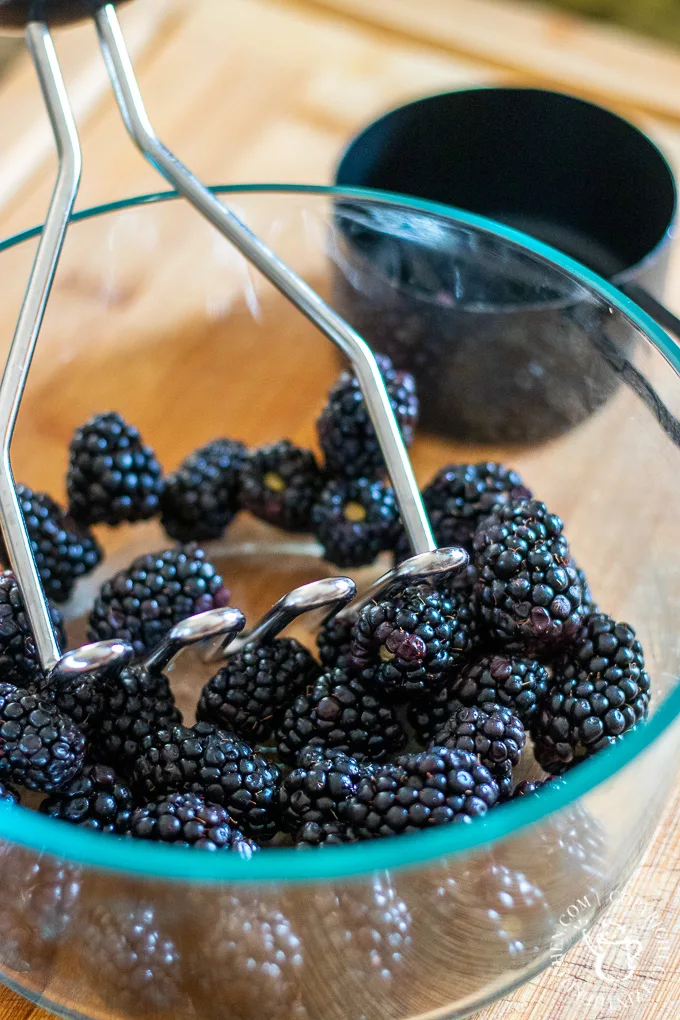 mashing blackberries in a bowl